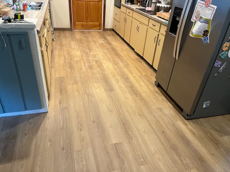 New light wood-look flooring installed through a kitchen